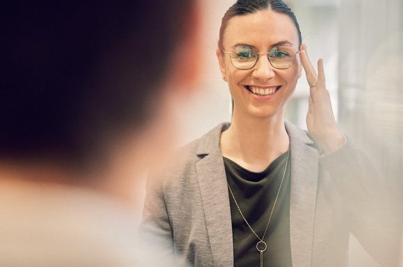 Junge Frau mit biometrischer Gleitsichtbrille vor dem Spiegel