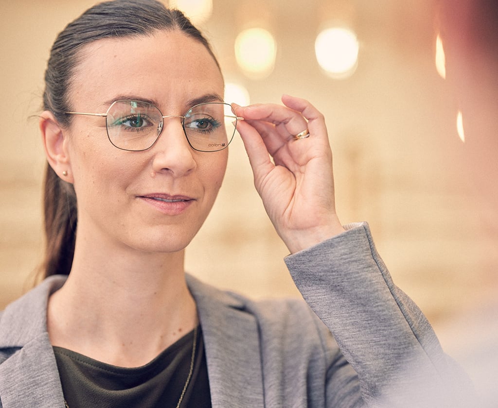 Junge Frau probiert eine Brillenfassung von Colibris an