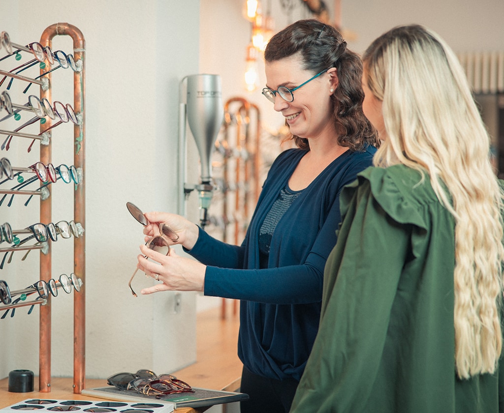 Beratung zur Auswahl von Sonnenbrillen bei Top Optik Stuttgart, verschiedene Brillenmodelle am Brillenständer